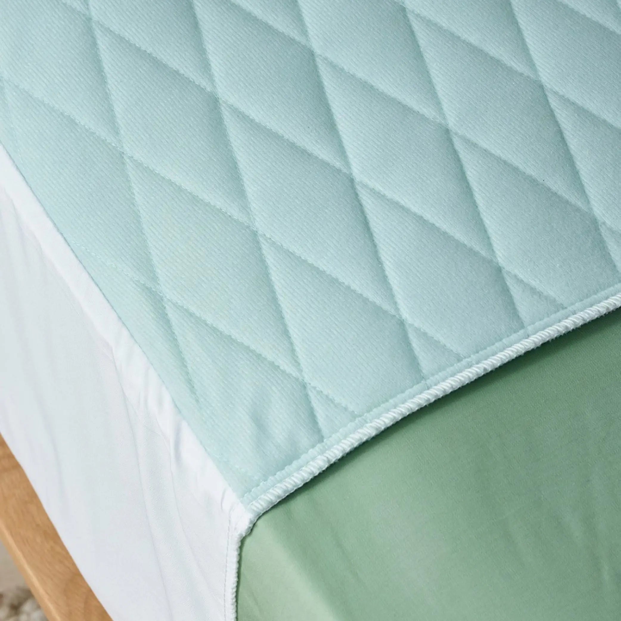 Close-up view of a quilted blue waterproof bed pad, also know as "kylie" bed pad, designed for incontinence protection. Featuring a soft, absorbent, and breathable fabric with a secure fit.