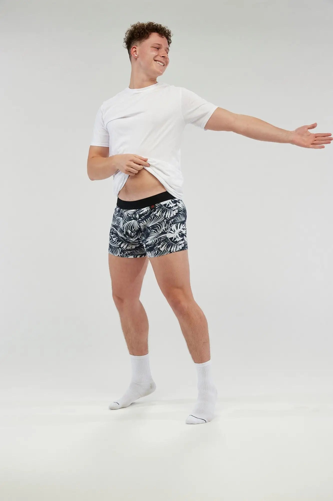 Teen boy wearing stylish black and white tropical print incontinence boxer briefs with a comfortable, discreet fit. Made from moisture-wicking, leak-proof fabric, these absorbent underwear provide all-day protection and confidence. Designed for active lifestyles, these machine-washable boxers offer a secure waistband, breathable fabric, and a modern design for a seamless blend of function and style.