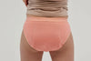 Rear view of teen girls' incontinence underwear in soft peach pink, designed with a discreet, absorbent core and leak-proof protection. Crafted from breathable, moisture-wicking fabric, these machine-washable, reusable briefs provide all-day comfort, security, and confidence. Featuring a seamless design and a snug yet flexible fit, ideal for active lifestyles.