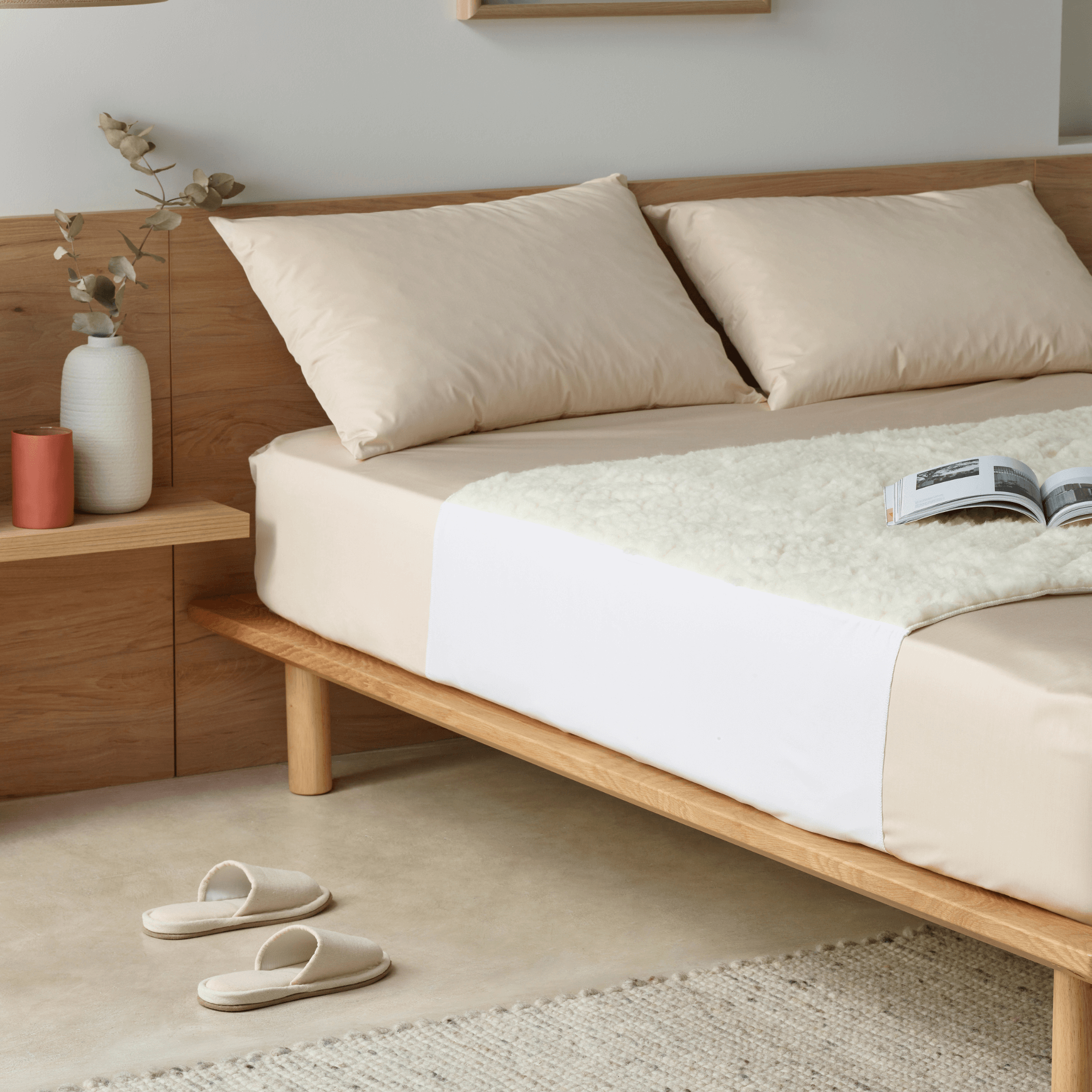 Luxury waterproof wool mattress topper, also known as kylie bed pad on a minimalist wooden bed, featuring soft cream pillows and a cosy fleece layer. Designed for ultimate comfort, this breathable, hypoallergenic protector keeps mattresses dry while regulating temperature for all-season use.